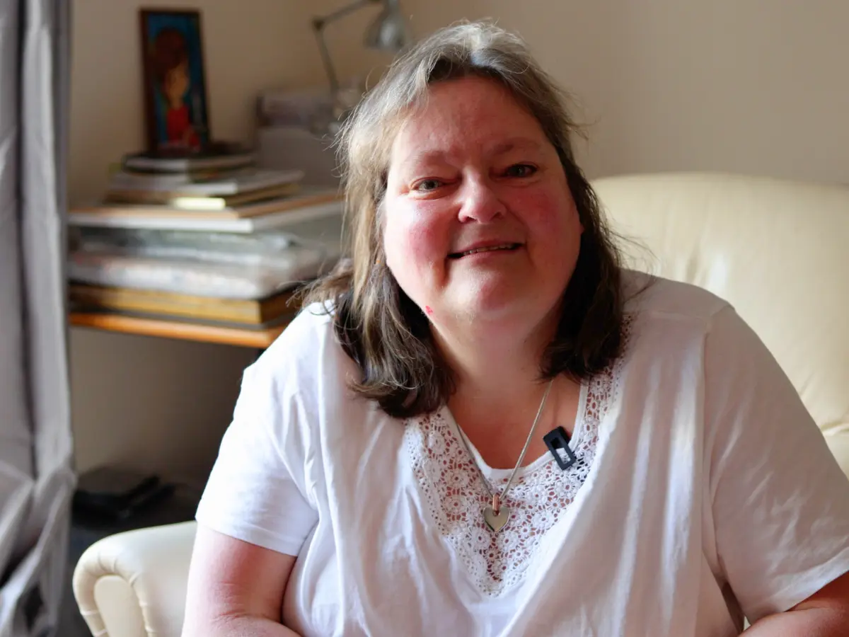 Unique senior care client, Heather, sat in her home smiling at the camera