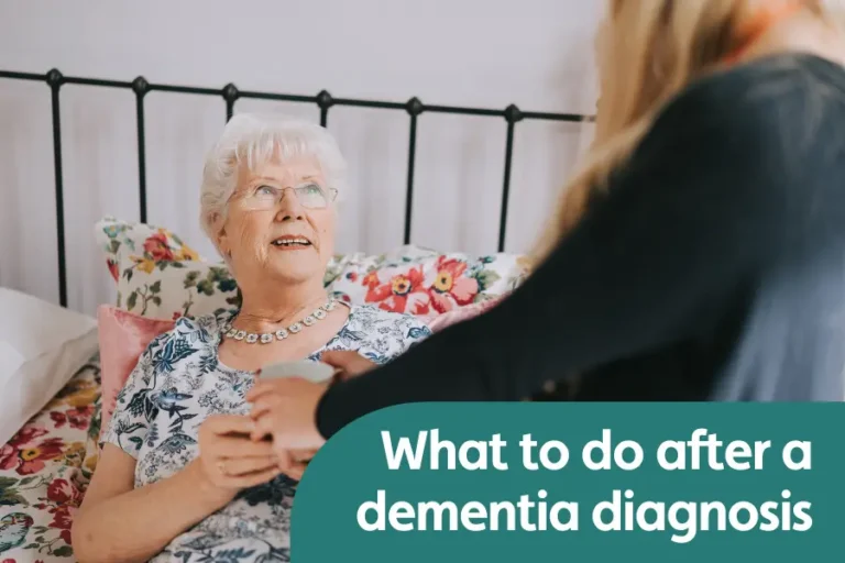 Featured image for blog around what to do after a dementia diagnosis. Image shows an older lady sat in bed smiling at her caregiver while being handed a cup of tea