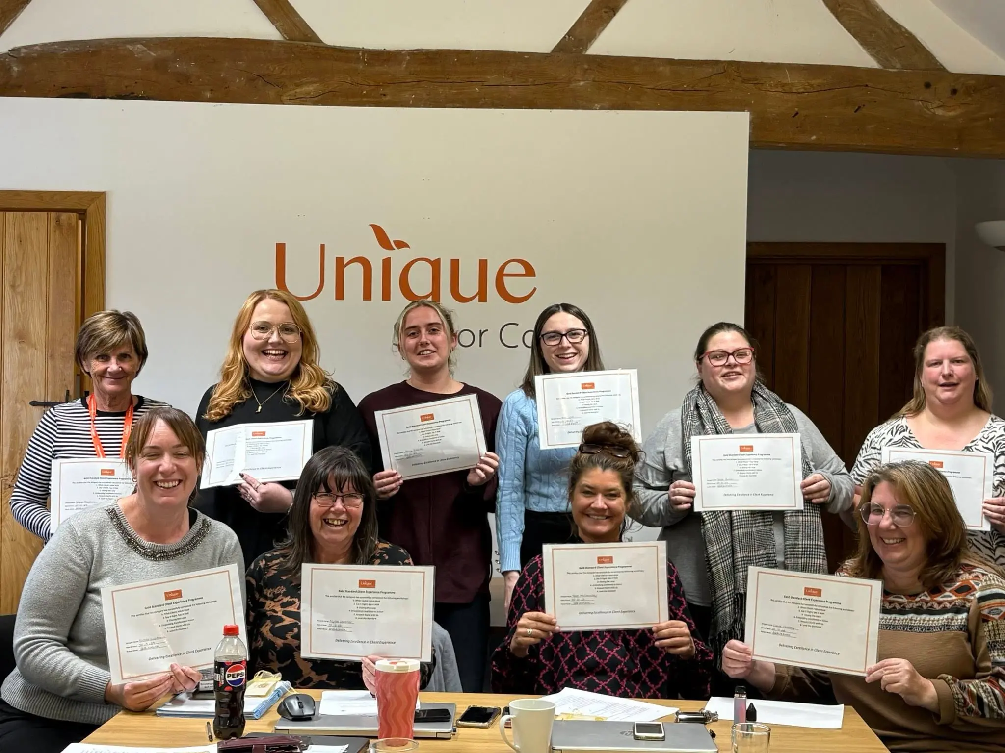 A group of managers, holding up their certificates for completing their client experience programme