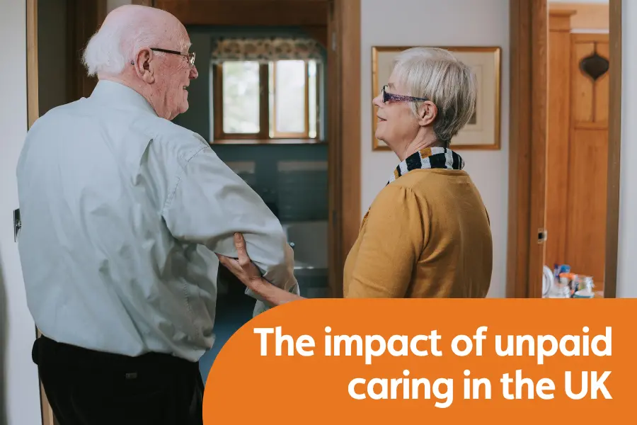 Featured image for blog on impact of unpaid caring in the UK. Image shows a lady supporting an elderly gentleman walking by holding an a hand under him arm as walking towards a door.